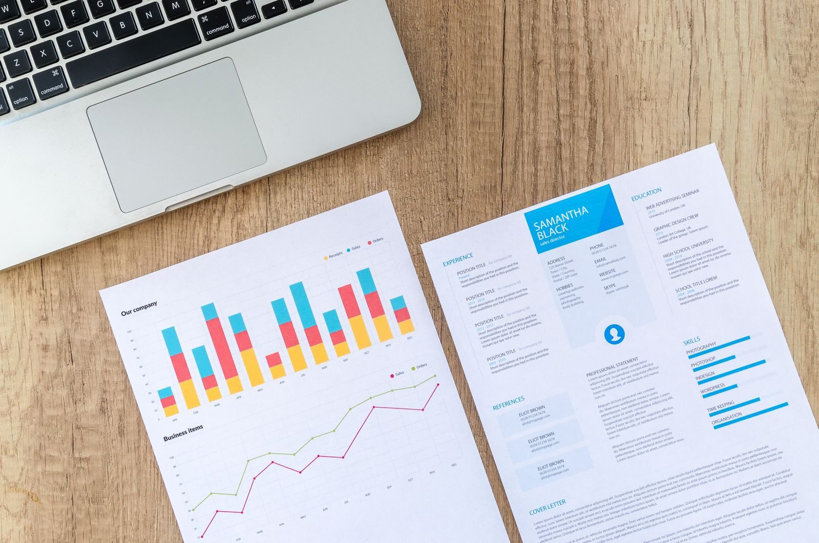 Printed sales analytics charts beside a laptop