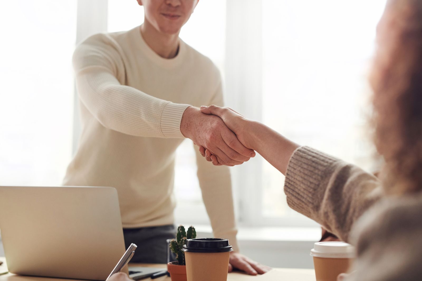 Business partners shaking hands over a table